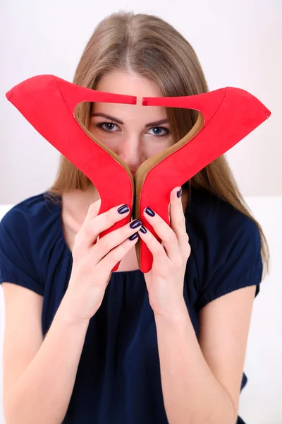 Menina sentada no sofá com sapatos vermelhos sexy, em casa fundo interior — Fotografia de Stock