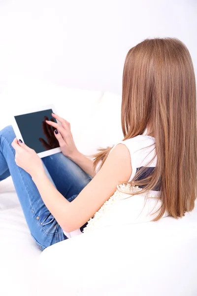 平板电脑在家里的沙发上休息的年轻女子 — 图库照片