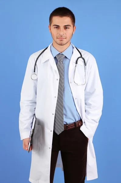 Dottore maschio in piedi con cartella, su sfondo blu — Foto Stock
