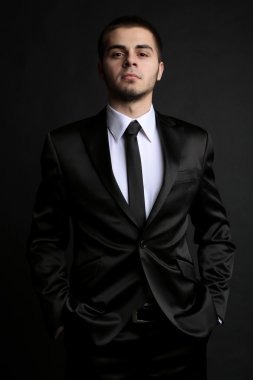 Handsome young man in suit on dark background clipart