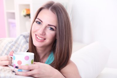 genç kadın kanepe evde sıcak bir içecek fincan ile dinlenme