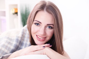 evde bir kanepede oturan genç bir kadın