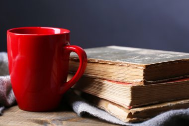 Kitaplar ve kareli koyu arka plan üzerine masada sıcak çay