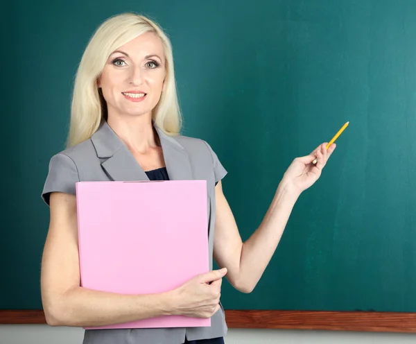 School teacher with folder near blackboard close-up — Stock Photo, Image