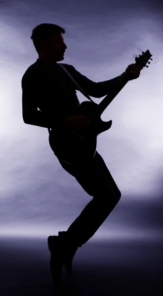 在暗灰色的背景上的吉他手剪影 — 图库照片