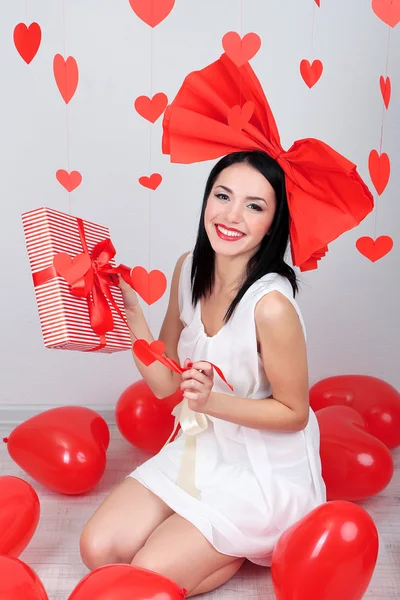 Jolie jeune femme avec cadeau et ballons dans la chambre le jour de la Saint-Valentin — Photo