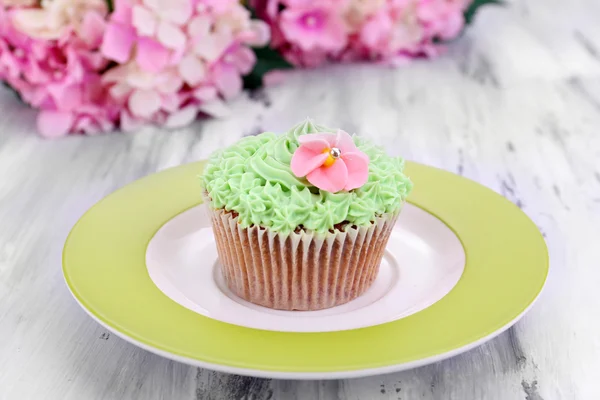 Välsmakande cupcake med smörkräm, på plattan, färg trä bakgrund — Stockfoto