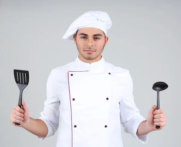 Profesjonalnym kucharzem w białym mundurze i kapelusz, na szarym tle — Zdjęcie stockowe