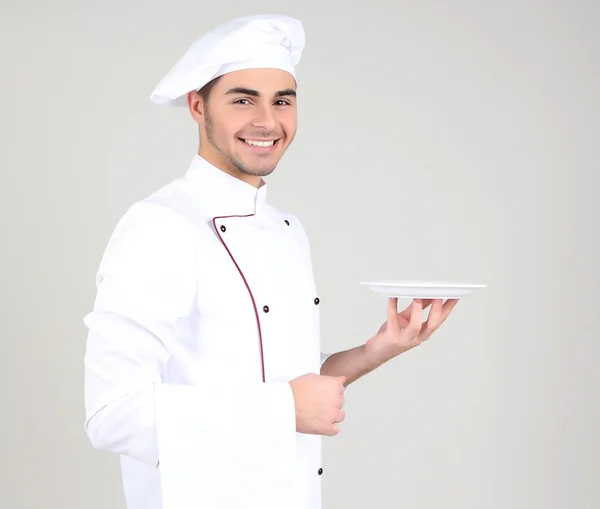 Professioneller Koch in weißer Uniform und Hut, auf grauem Hintergrund — Stockfoto