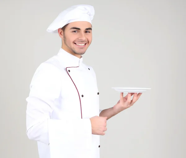 Professionell kock i vit uniform och hatt, på grå bakgrund — Stockfoto