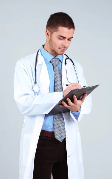 Arzt steht mit Ordner auf grauem Hintergrund — Stockfoto