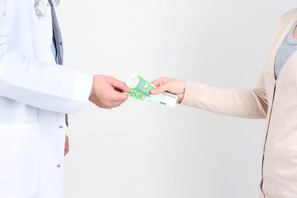 Erkek doktor hastadan, para alma üzerine beyaz izole — Stok fotoğraf