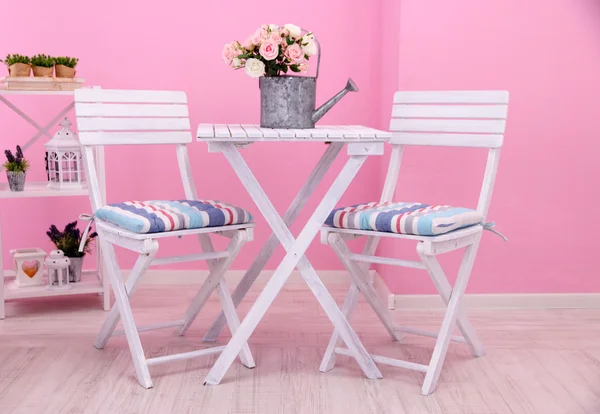 Tuin stoelen en tafel met bloemen op de planken op roze achtergrond — Stockfoto