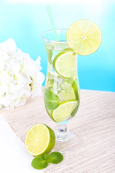 Bicchiere di cocktail con lime e menta sul tavolo su sfondo azzurro — Foto Stock