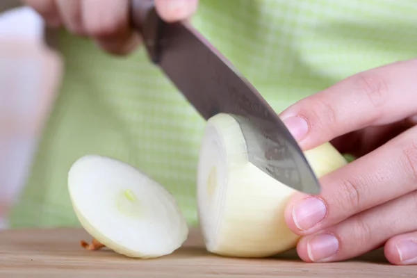 Female hands cutting bulb onion, on kitchen background — Stock Photo, Image