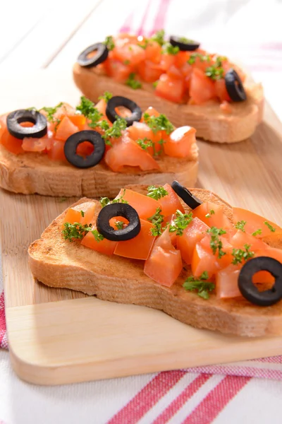 Lahodná bruschetta s rajčaty na řezací desce zblízka — Stock fotografie