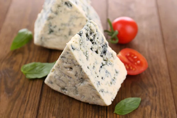 Schmackhafter Blauschimmelkäse mit Basilikum und Tomaten, auf Holztisch — Stockfoto