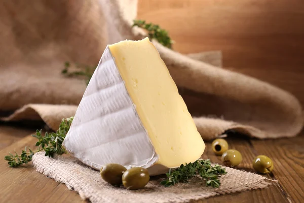 Вкусный сыр Камамбер с тимьяном и оливками, на деревянном столе — стоковое фото