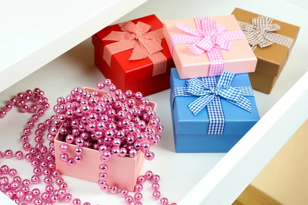 Geschenkboxen und Perlen in offener Schreibtischschublade in Nahaufnahme — Stockfoto