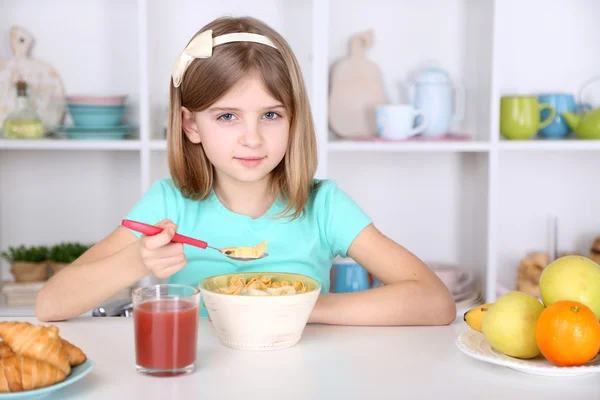 O fetiță frumoasă care mănâncă micul dejun în bucătărie acasă — Fotografie, imagine de stoc