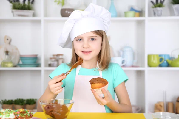 Klein meisje cupcakes in keuken thuis verfraaien — Stockfoto