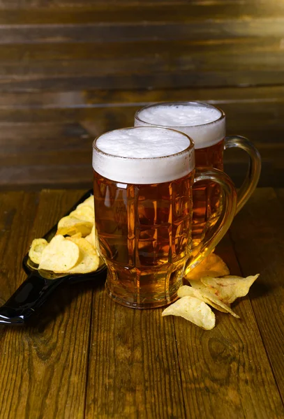 Vasos de cerveza con merienda en la mesa sobre fondo de madera — Foto de Stock