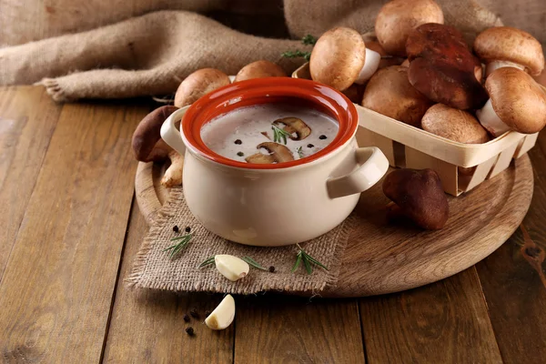 Houbová polévka v hrnci, na dřevěný stůl, na pozadí pytloviny — Stock fotografie