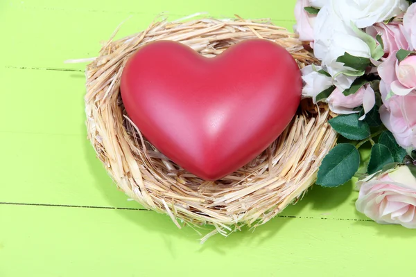 Decoratieve hart in nest, op een houten achtergrond kleur — Stockfoto