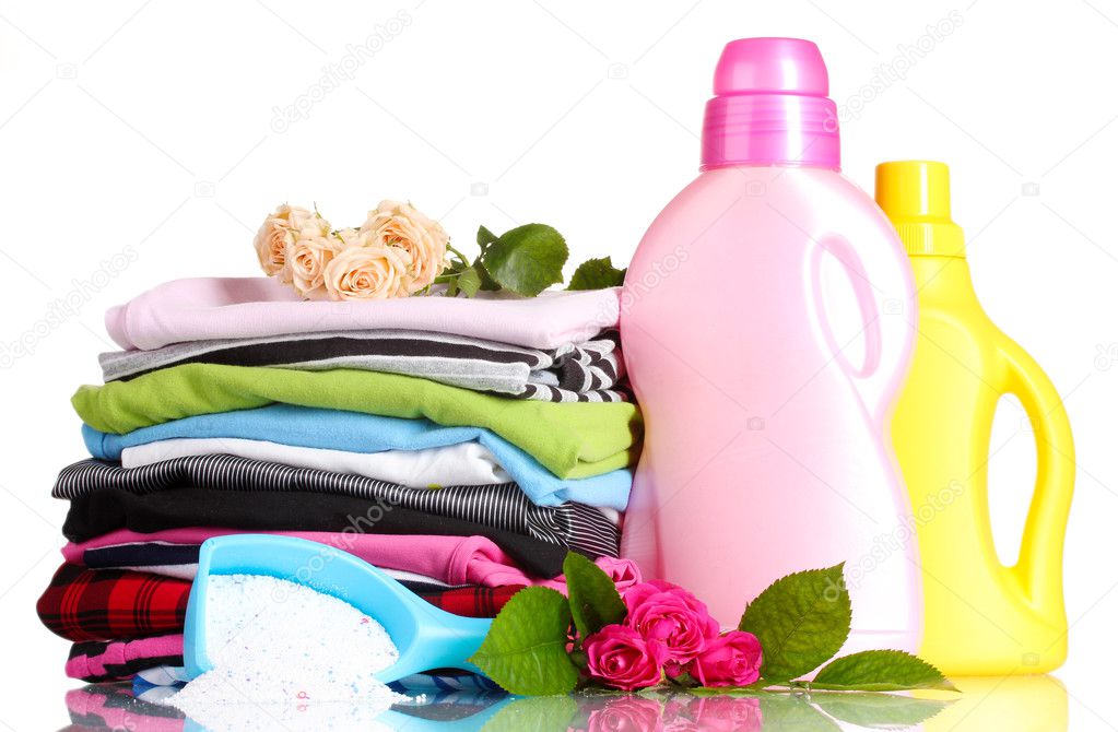 Detergent with washing powder and pile of colorful clothes isolated on white