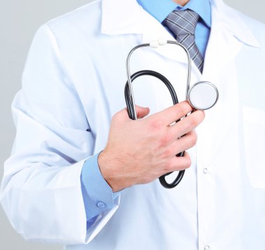 Erkek Doktor gri arka planda duruyor