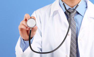 mavi arka plan üzerinde duran erkek doktor