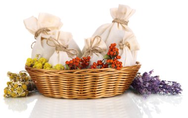 Tekstil poşet torbalar içinde kuru çiçekler, otlar ve üzerinde beyaz izole meyveleri hasır sepet,