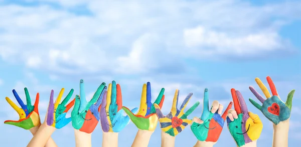 Mãos pintadas com sorriso no fundo do céu — Fotografia de Stock