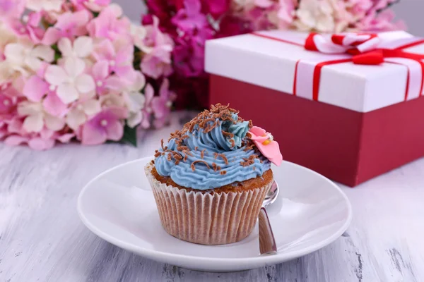 Smakelijke cupcake met boter room, op de plaat, op een houten achtergrond kleur — Stockfoto