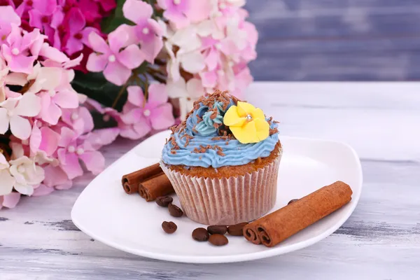 Cupcake lezat dengan krim mentega, di piring, pada warna latar belakang kayu — Stok Foto