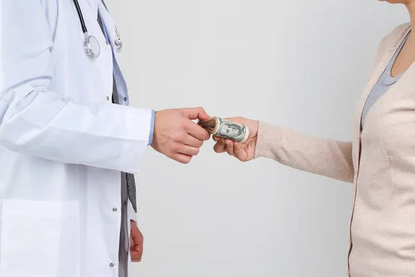 Muž lékař obdrží peníze od pacienta, izolované na bílém — Stock fotografie