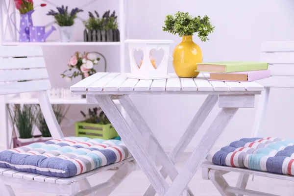 Sillas de jardín y mesa con flores en estantes sobre fondo blanco —  Fotos de Stock