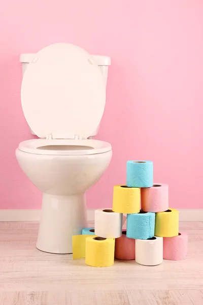 White toilet bowl and colorful rolls of toilet paper, in  bathroom — Stock Photo, Image