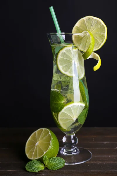 Glass of cocktail with lime and mint on table on black background — Stock Photo, Image