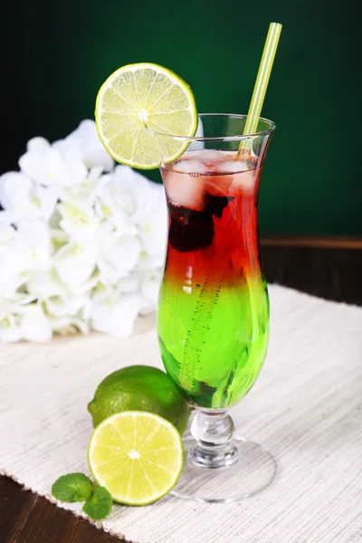 Glass of cocktail on table on dark green background — Stock Photo, Image