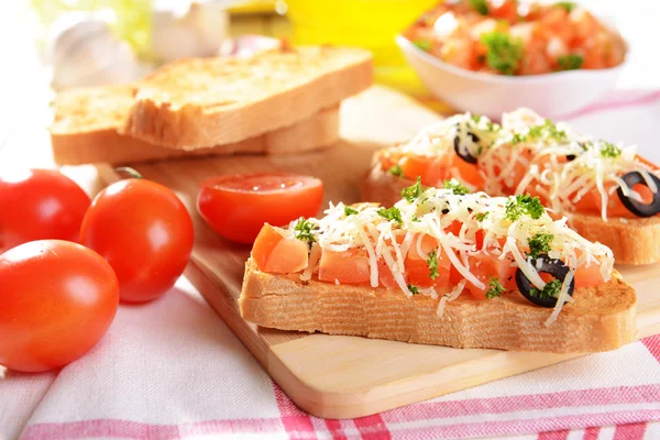 Deliciosa bruschetta con tomates en la tabla de cortar de cerca —  Fotos de Stock