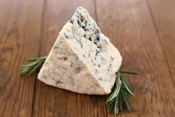 Smakelijke blauwe kaas met rozemarijn, op houten tafel — Stockfoto