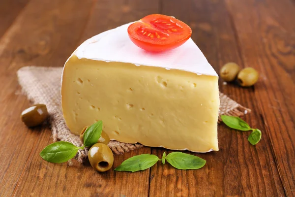 Smakelijke camembert kaas met tomaat, basilicum en olijven, op houten tafel — Stockfoto