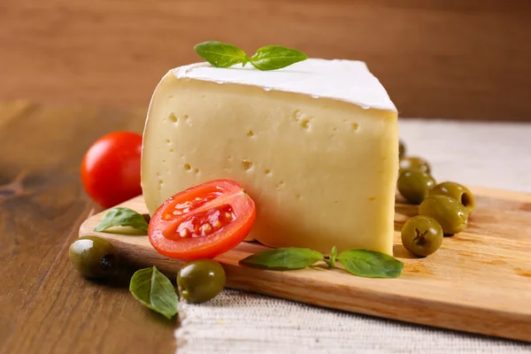 Queijo saboroso Camembert com tomate, azeitonas e manjericão, sobre mesa de madeira — Fotografia de Stock