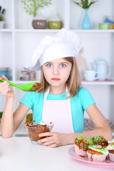 Little girl eating cream in kitchen at home — Stock Photo, Image