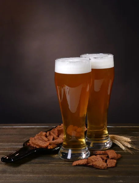 Glazen bier met snack op tafel op donkere achtergrond — Stockfoto