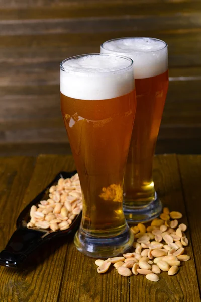 Ποτήρια μπύρα με σνακ στο τραπέζι σε ξύλινα φόντο — Φωτογραφία Αρχείου