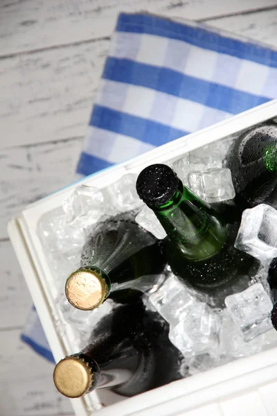 Pecho de hielo lleno de bebidas en botellas en servilleta de color, sobre fondo de madera —  Fotos de Stock