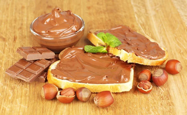 Brood met zoete chocolade hazelnoot verspreid over houten achtergrond — Stockfoto