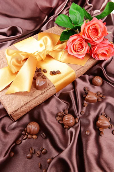 Heerlijke chocolade in doos met bloemen op bruine achtergrond — Stockfoto